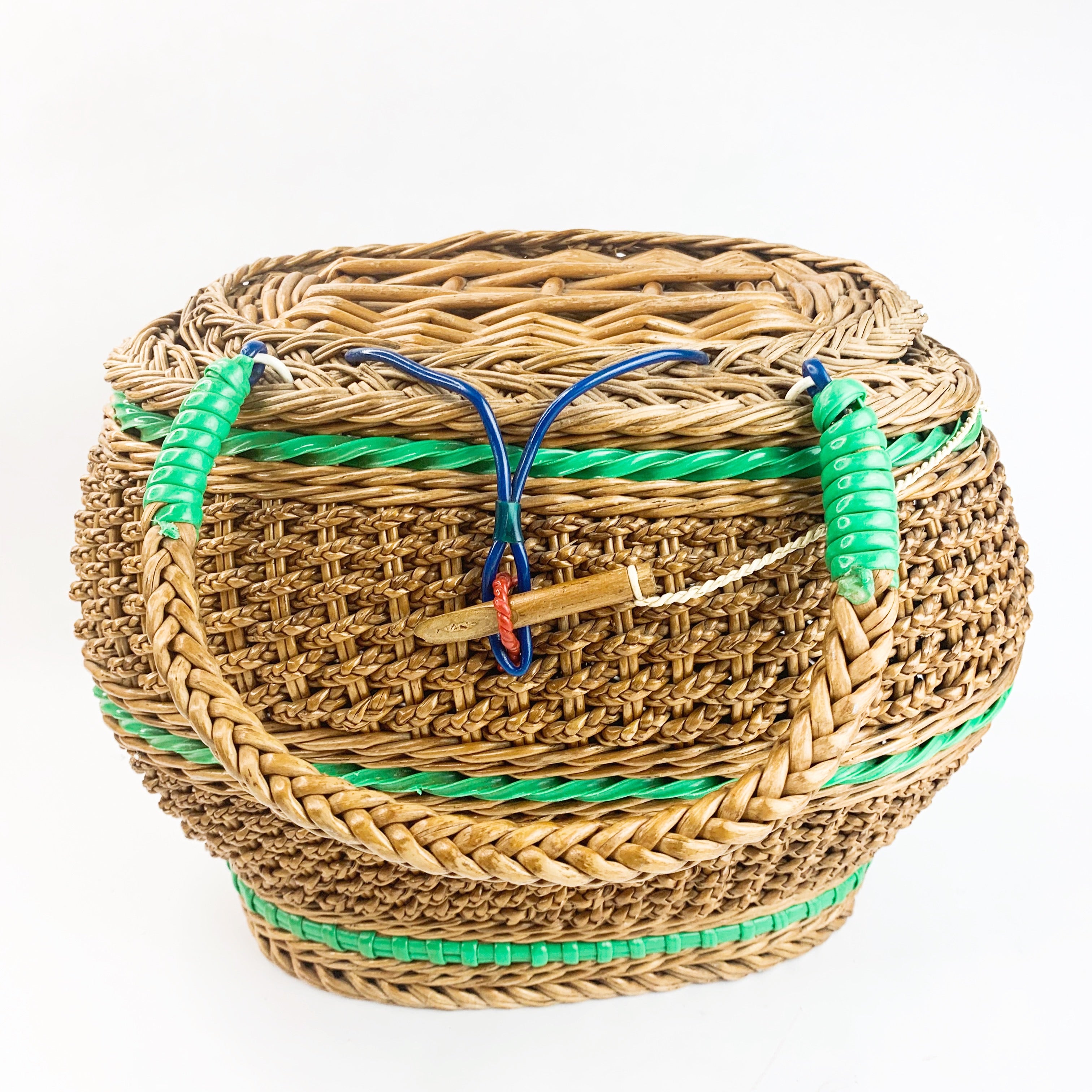 Woven basket purse with floral design from Maes Millinery Shop. A purse  with leather handles made from woven grass like a basket, with the floral  pattern on the front and lid executed